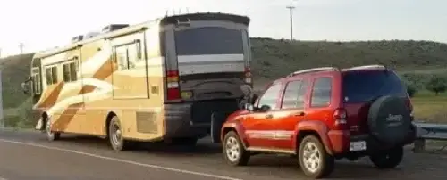 Brown Motorhome towing Red Jeep